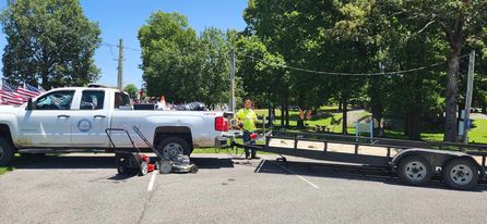 Photo of a truck and a trailer with lawn mowers getting ready to do public work